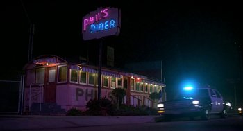 Movie still from “Night of the Creeps” (1986), directed by Fred Dekker – A neon sign lit up at night in front of a diner; Wide shot, Low angle