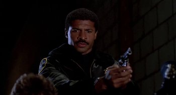 Movie still from “Night of the Creeps” (1986), directed by Fred Dekker – A man holding a gun while standing in a dark room; Close Up shot, Low angle