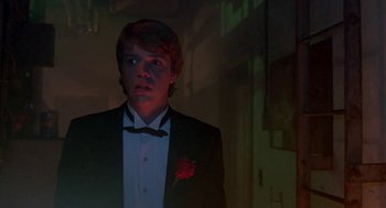 Movie still from “Night of the Creeps” (1986), directed by Fred Dekker – A man in a tuxedo standing in a dark room; Medium shot, Low angle