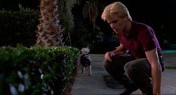 Movie still from “Night of the Creeps” (1986), directed by Fred Dekker – A man kneeling down next to a dog on a sidewalk; Medium shot, Low angle