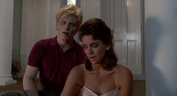 Movie still from “Night of the Creeps” (1986), directed by Fred Dekker – A man and a woman sitting in front of each other in a room; Medium shot, Over the shoulder angle