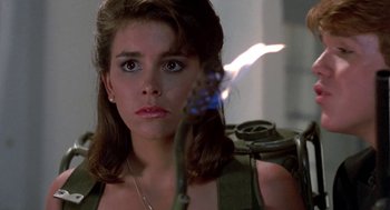 Movie still from “Night of the Creeps” (1986), directed by Fred Dekker – A person holding a flower in a room; Close Up shot, Low angle