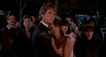 Movie still from “Night of the Creeps” (1986), directed by Fred Dekker – A man and a woman in formal wear standing next to each other in a crowd; Medium shot, Low angle