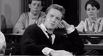 Movie still from “Night of the Eagle” (1962), directed by Sidney Hayers – A young man sitting next to another young man in a room; Close Up shot, High angle