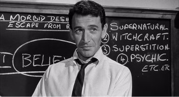 Movie still from “Night of the Eagle” (1962), directed by Sidney Hayers – Black and white photograph of a man in front of a chalkboard; Medium shot, High angle