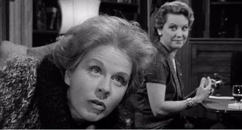 Movie still from “Night of the Eagle” (1962), directed by Sidney Hayers – Two women are looking at the camera in a black and white photo; Close Up shot, Over the shoulder angle