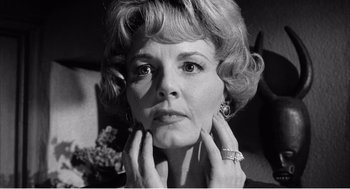 Movie still from “Night of the Eagle” (1962), directed by Sidney Hayers – An older woman with her hands under her chin; Close Up shot, Low angle