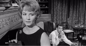 Movie still from “Night of the Eagle” (1962), directed by Sidney Hayers – An old photo of a man and a woman sitting in a chair; Medium shot, Low angle