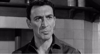 Movie still from “Night of the Eagle” (1962), directed by Sidney Hayers – Black and white photograph of a man looking at the camera; Close Up shot, Low angle