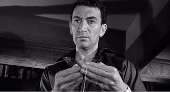 Movie still from “Night of the Eagle” (1962), directed by Sidney Hayers – A black - and - white photo of a man knitting; Close Up shot, Low angle