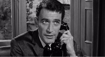 Movie still from “Night of the Eagle” (1962), directed by Sidney Hayers – A black and white photo of a man talking on a phone; Close Up shot, High angle