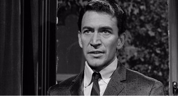 Movie still from “Night of the Eagle” (1962), directed by Sidney Hayers – Black and white photograph of a man wearing a suit and tie; Close Up shot, Over the shoulder angle