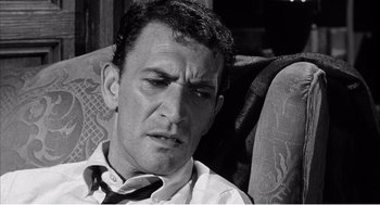 Movie still from “Night of the Eagle” (1962), directed by Sidney Hayers – A man sitting on top of a couch with his eyes closed; Close Up shot, High angle