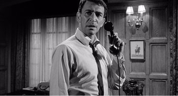 Movie still from “Night of the Eagle” (1962), directed by Sidney Hayers – A black and white photo of a man holding a phone; Close Up shot, Low angle