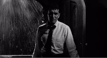 Movie still from “Night of the Eagle” (1962), directed by Sidney Hayers – A black and white photo of a man wearing a tie; Medium shot, Low angle