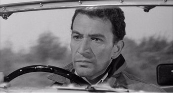 Movie still from “Night of the Eagle” (1962), directed by Sidney Hayers – Black and white photograph of a man looking at the camera; Close Up shot, High angle