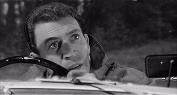 Movie still from “Night of the Eagle” (1962), directed by Sidney Hayers – A black and white photo of a man talking on a cell phone; Close Up shot, High angle