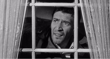 Movie still from “Night of the Eagle” (1962), directed by Sidney Hayers – A black and white photo of a man looking through a window; Close Up shot, Low angle