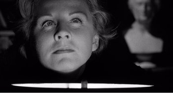Movie still from “Night of the Eagle” (1962), directed by Sidney Hayers – Black and white photograph of a woman looking at her reflection in a mirror; Close Up shot, Low angle