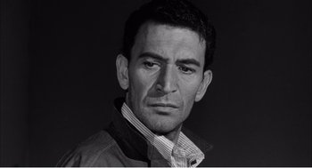 Movie still from “Night of the Eagle” (1962), directed by Sidney Hayers – Black and white photograph of a man with a serious look; Close Up shot, Low angle
