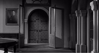 Movie still from “Night of the Eagle” (1962), directed by Sidney Hayers – An open door leading to a large arched doorway; Extreme Wide shot, High angle