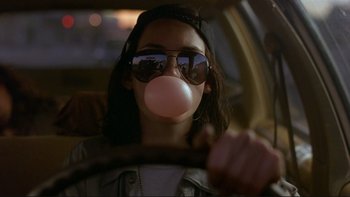Movie still from “Night on Earth” (1991), directed by Jim Jarmusch – A woman in sunglasses blowing a bubble with a gum bubble; Close Up shot, Low angle