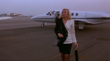 Movie still from “Night on Earth” (1991), directed by Jim Jarmusch – A woman in a black and white suit standing in front of an airplane; Medium shot, Low angle