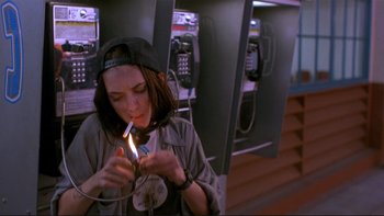 Movie still from “Night on Earth” (1991), directed by Jim Jarmusch – A woman lighting a cigarette on a phone booth; Medium shot, High angle