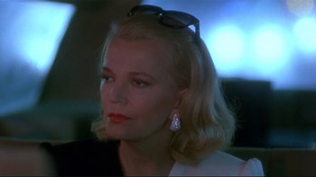 Movie still from “Night on Earth” (1991), directed by Jim Jarmusch – A woman with blonde hair wearing sunglasses and a white shirt; Close Up shot, Over the shoulder angle