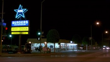 Movie still from “Night on Earth” (1991), directed by Jim Jarmusch – A night time view of a restaurant with a lot of lights on; Extreme Wide shot, Low angle