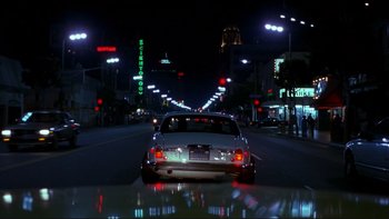 Movie still from “Night on Earth” (1991), directed by Jim Jarmusch – A car driving down a street at night; Extreme Wide shot, Low angle