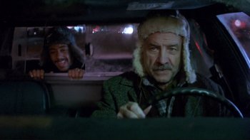 Movie still from “Night on Earth” (1991), directed by Jim Jarmusch – A man in a green jacket and a man in a white hat in the back of a car; Medium shot, Over the shoulder angle