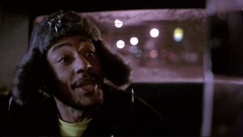 Movie still from “Night on Earth” (1991), directed by Jim Jarmusch – A man with a fur hat in a car with lights in the background; Close Up shot, Low angle