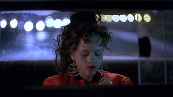 Movie still from “Night on Earth” (1991), directed by Jim Jarmusch – A woman in a red shirt is looking at her cell phone; Close Up shot, Low angle