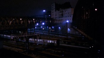 Movie still from “Night on Earth” (1991), directed by Jim Jarmusch – A train yard at night lit up by street lights; Extreme Wide shot, High angle