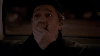 Movie still from “Night on Earth” (1991), directed by Jim Jarmusch – A man in a black hat and a black jacket is holding his hand to his mouth; Close Up shot, Over the shoulder angle