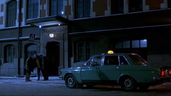 Movie still from “Night on Earth” (1991), directed by Jim Jarmusch – An old car parked in front of a building at night; Wide shot, Low angle