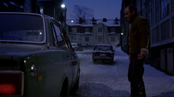 Movie still from “Night on Earth” (1991), directed by Jim Jarmusch – A man standing next to a parked car on a snowy street; Wide shot, High angle