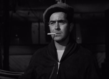 Movie still from “Nightmare Alley” (1947), directed by Edmund Goulding – A black and white photo of a man smoking a cigarette; Close Up shot, Low angle