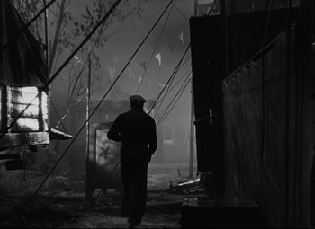 Movie still from “Nightmare Alley” (1947), directed by Edmund Goulding – A man walking in a dark alley with a tree in the background; Wide shot, Low angle