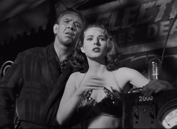 Movie still from “Nightmare Alley” (1947), directed by Edmund Goulding – A man standing next to a woman in a bra; Medium shot, Low angle