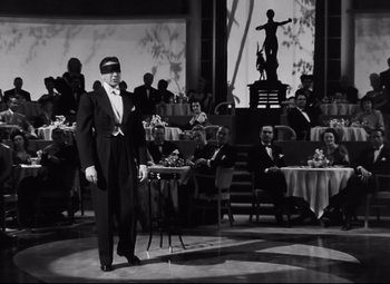 Movie still from “Nightmare Alley” (1947), directed by Edmund Goulding – A man standing in front of an audience wearing a blindfold; Wide shot, Low angle