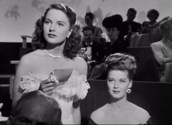 Movie still from “Nightmare Alley” (1947), directed by Edmund Goulding – Two women in formal wear in an auditorium; Medium shot, Low angle