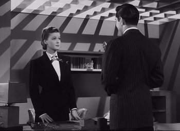 Movie still from “Nightmare Alley” (1947), directed by Edmund Goulding – A man and a woman in a suit and tie talking to each other; Medium shot, Over the shoulder angle