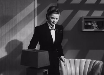 Movie still from “Nightmare Alley” (1947), directed by Edmund Goulding – A black and white photo of a woman in a suit; Medium shot, High angle