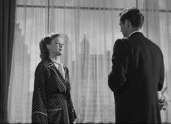 Movie still from “Nightmare Alley” (1947), directed by Edmund Goulding – A man and a woman standing next to each other in front of a window; Medium shot, Low angle