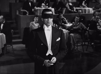 Movie still from “Nightmare Alley” (1947), directed by Edmund Goulding – A black and white photo of a man in a tuxedo; Medium shot, High angle