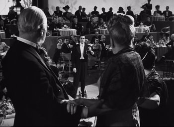 Movie still from “Nightmare Alley” (1947), directed by Edmund Goulding – A man in a suit standing in front of an audience; Wide shot, Over the shoulder angle