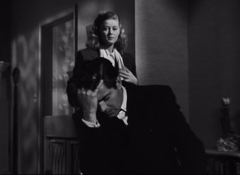 Movie still from “Nightmare Alley” (1947), directed by Edmund Goulding – A man and a woman sitting next to each other in front of a window; Medium shot, Low angle