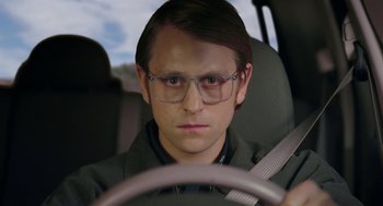 Movie still from “Nightmare Cinema” (2018), directed by Alejandro Brugués – A man wearing glasses sitting in the driver's seat of a car; Close Up shot, Over the shoulder angle